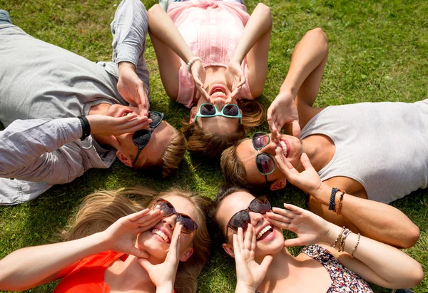 Group of smiling friends lying on grass outdoors — Stock Photo, Image