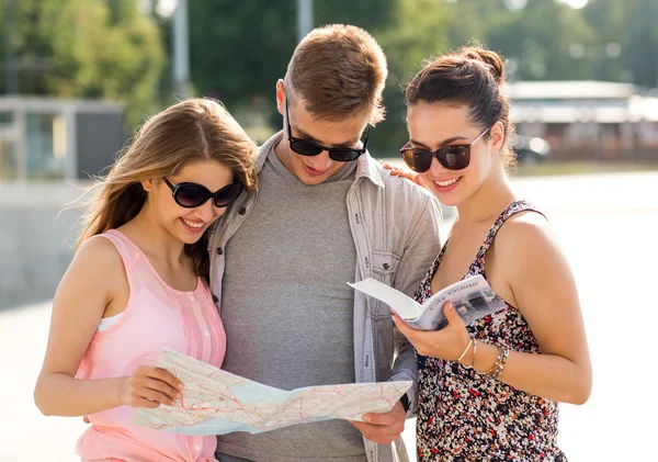 Amigos sonrientes con mapa y guía de la ciudad al aire libre — Foto de Stock