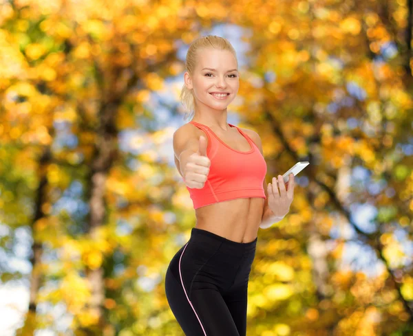 Mujer deportiva sonriente con teléfono inteligente — Foto de Stock