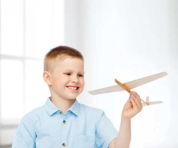 Smiling little boy holding a wooden airplane model — Stock Photo, Image