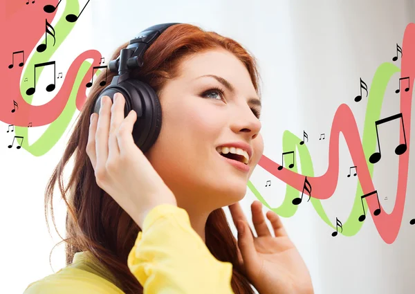 Sonriente chica joven en los auriculares en casa —  Fotos de Stock