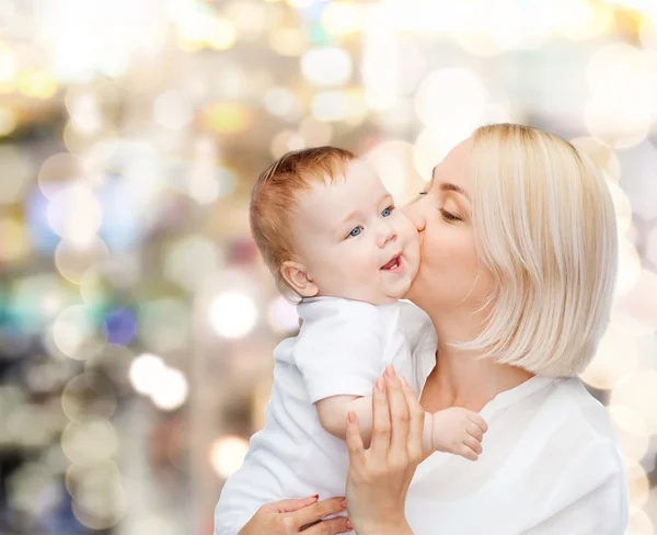 Glückliche Mutter küsst lächelndes Baby — Stockfoto