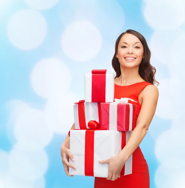 Lachende vrouw in rode jurk met geschenkdozen — Stockfoto