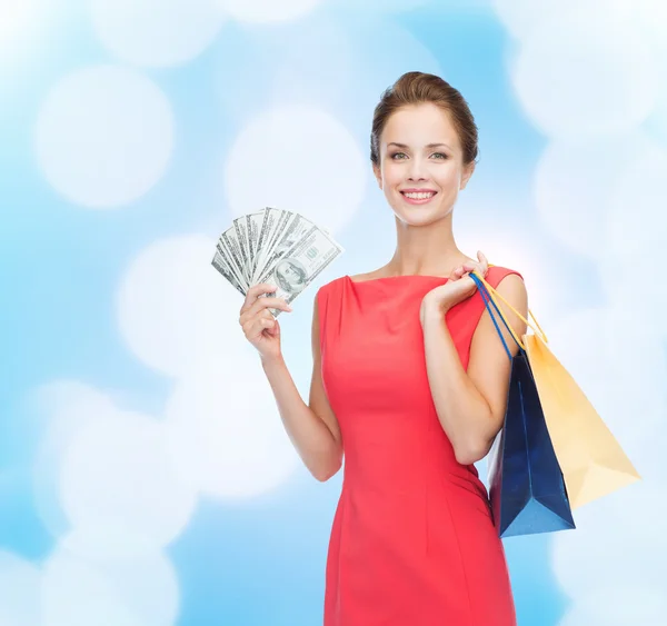 Mujer sonriente en vestido rojo con bolsas de compras —  Fotos de Stock