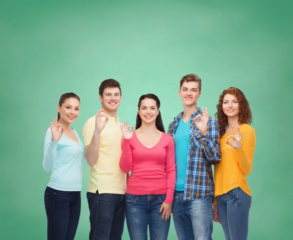 Группа улыбающихся подростков над зеленой доской — стоковое фото