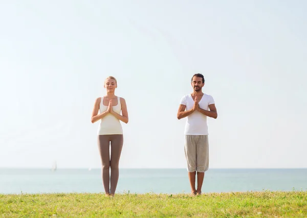 Çift gülümseyen açık havada yapım yoga egzersizleri — Stok fotoğraf