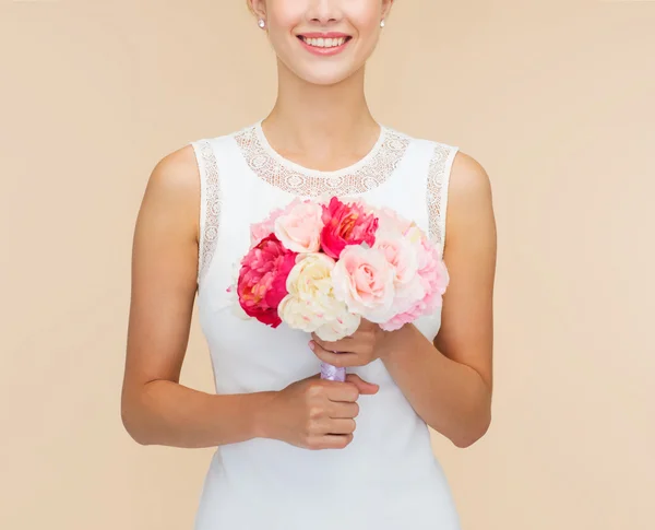 Lachende vrouw in witte jurk met boeket rozen — Stockfoto