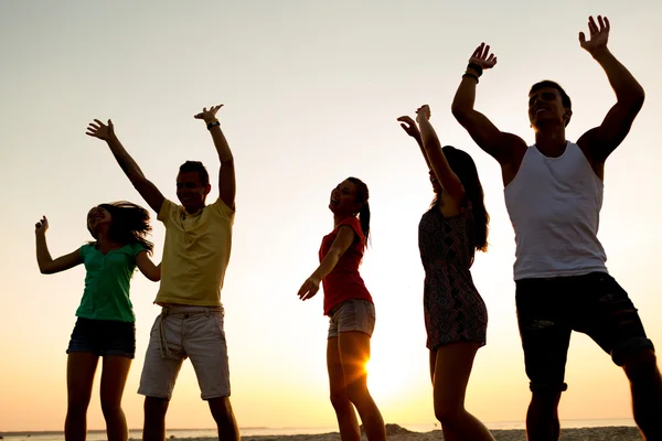 Lachende vrienden dansen op zomer strand — Stockfoto