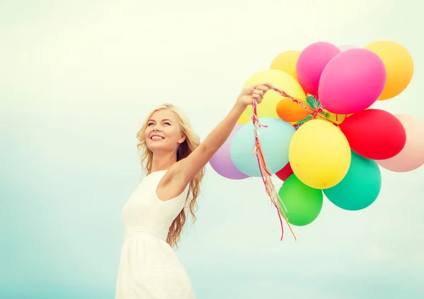 Femme souriante avec des ballons colorés à l'extérieur — Photo