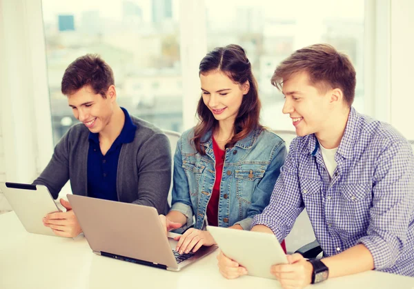 Trois étudiants souriants avec ordinateur portable et tablette PC — Photo