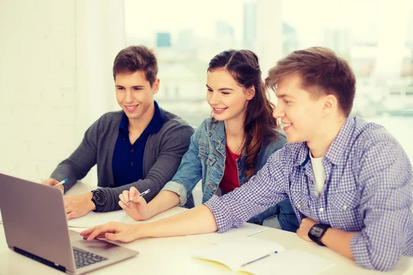 Tres estudiantes sonrientes con portátil y cuadernos —  Fotos de Stock