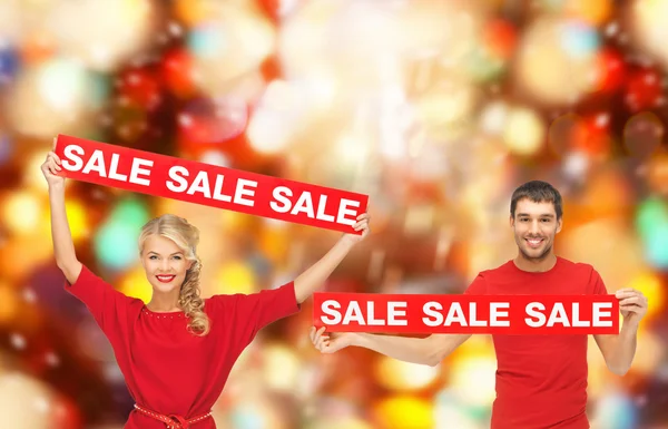 Hombre y mujer sonrientes con letreros rojos de venta — Foto de Stock