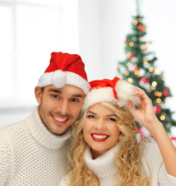 Sonriente pareja en suéteres y sombreros de santa ayudante — Foto de Stock