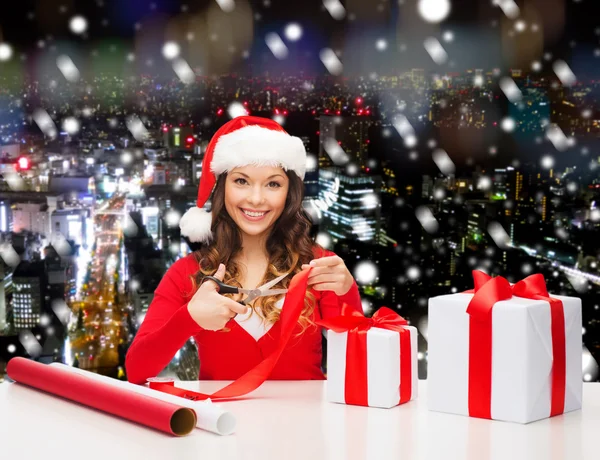 Sonriente mujer en santa helper sombrero embalaje caja de regalo —  Fotos de Stock