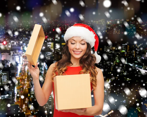 Donna sorridente in cappello Babbo Natale helper con confezione regalo — Foto Stock