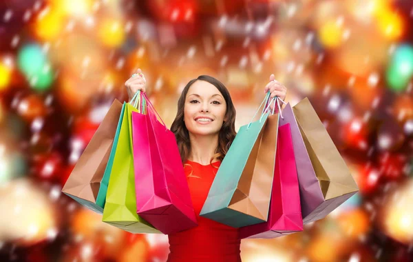 Mujer en vestido rojo con coloridas bolsas de compras —  Fotos de Stock
