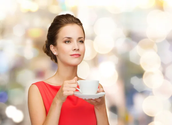 Lachende vrouw in rode jurk met kop koffie — Stockfoto