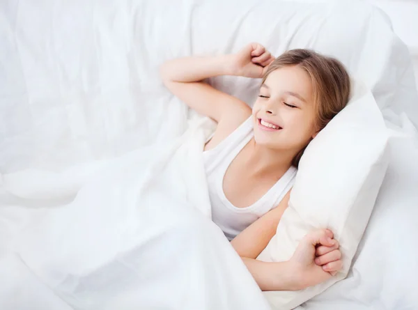 Χαμογελαστό κορίτσι παιδί ξυπνήσει στο κρεβάτι στο σπίτι — Φωτογραφία Αρχείου