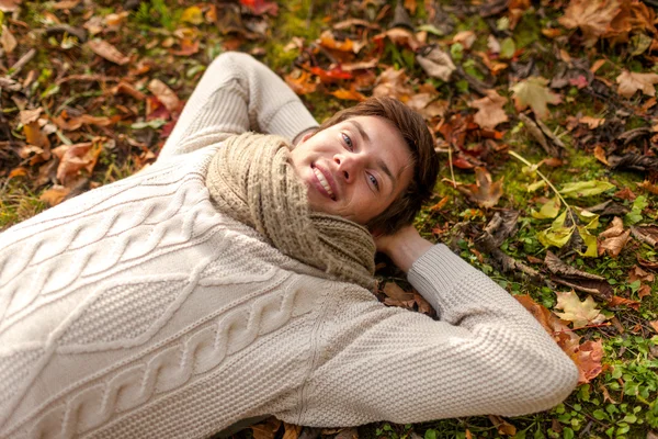 Close up van lachende jonge man liggen in de herfst park — Stockfoto