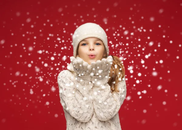 Happy girl in winter clothes blowing on palms Stock Photo