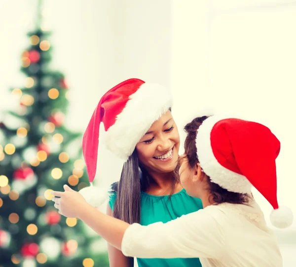 Hugging mother and daughter in santa helper hats — Stock Photo, Image