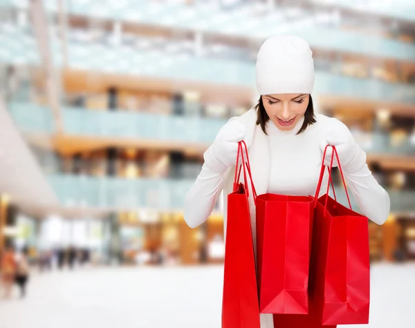 Sorrindo jovem mulher com sacos de compras vermelhos — Fotografia de Stock
