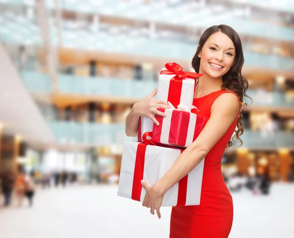 Lächelnde Frau im roten Kleid mit Geschenkschachteln — Stockfoto