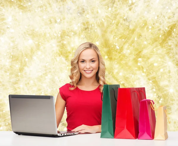 Mujer sonriente en camisa roja con regalos y portátil — Foto de Stock