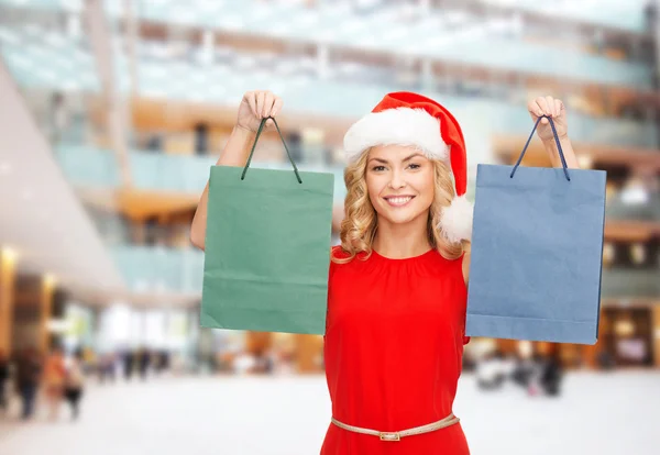 Vrouw in helper kerstmuts met shopping tassen — Stockfoto