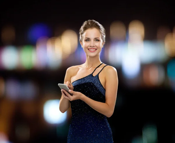 Lachende vrouw in avondjurk met smartphone — Stockfoto