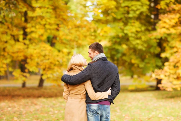 Usmíval se, pár objímat v podzimním parku zezadu — Stock fotografie
