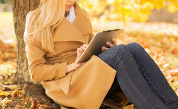 Молодая женщина с планшетным компьютером в осеннем парке — стоковое фото