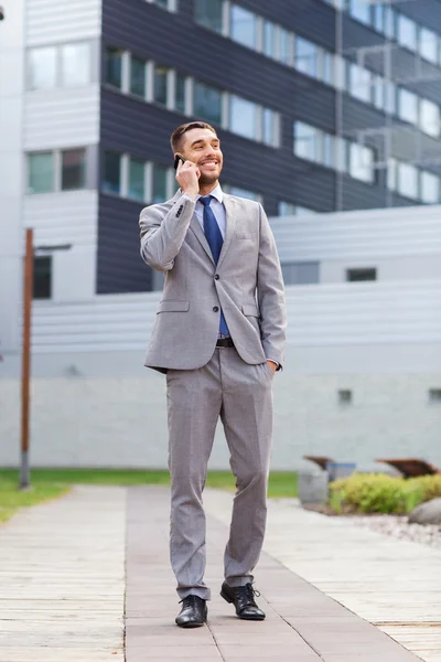 Homem de negócios sorridente com smartphone ao ar livre — Fotografia de Stock