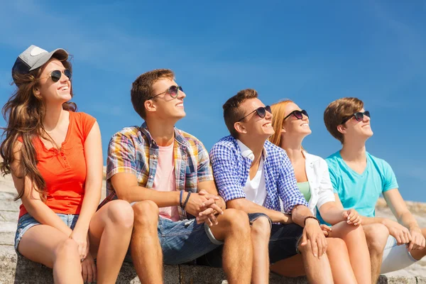 Grupo de amigos sonriendo sentados en la calle de la ciudad — Foto de Stock