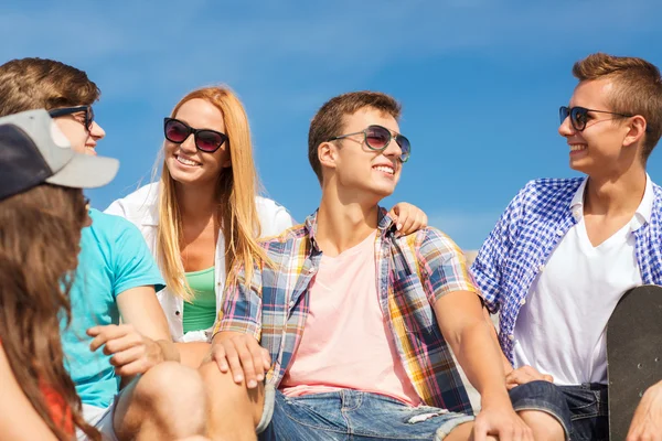 Group of smiling friends sitting on city street — Stock Photo, Image