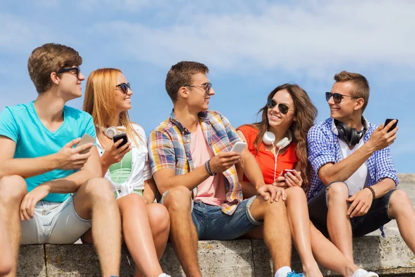 Groupe d'amis souriants avec smartphones en plein air — Photo