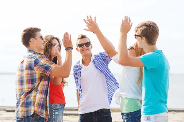 Groep lachende vrienden maken hoge vijf buitenshuis — Stockfoto