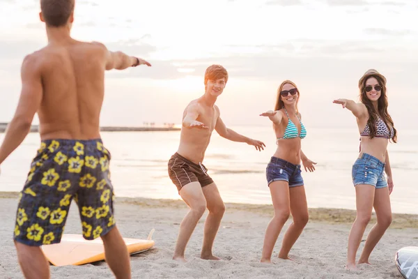 Ler vänner i solglasögon med surfar på stranden — Stockfoto