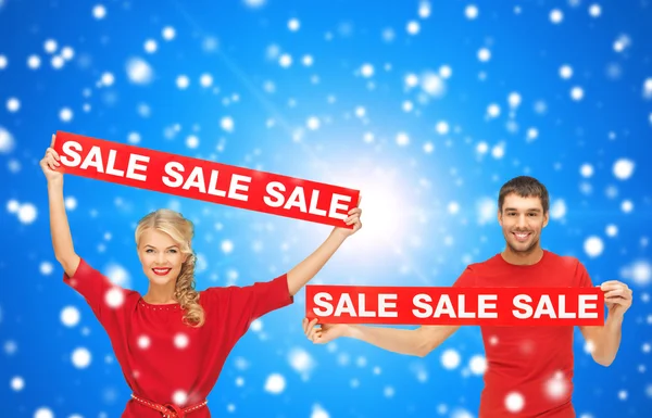 Smiling man and woman with red sale signs — Stock Photo, Image