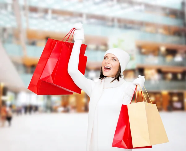 Sorrindo jovem mulher com sacos de compras vermelhos — Fotografia de Stock