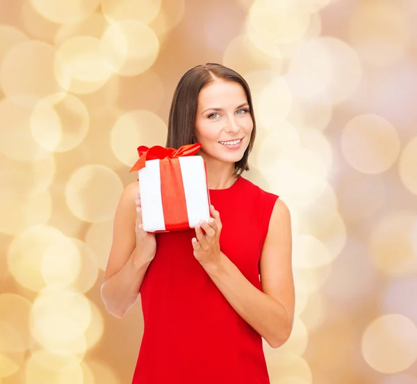 Leende kvinna i röd klänning med presentask — Stockfoto
