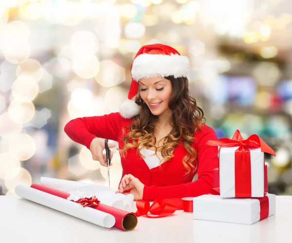 Sonriente mujer en santa helper sombrero embalaje caja de regalo —  Fotos de Stock