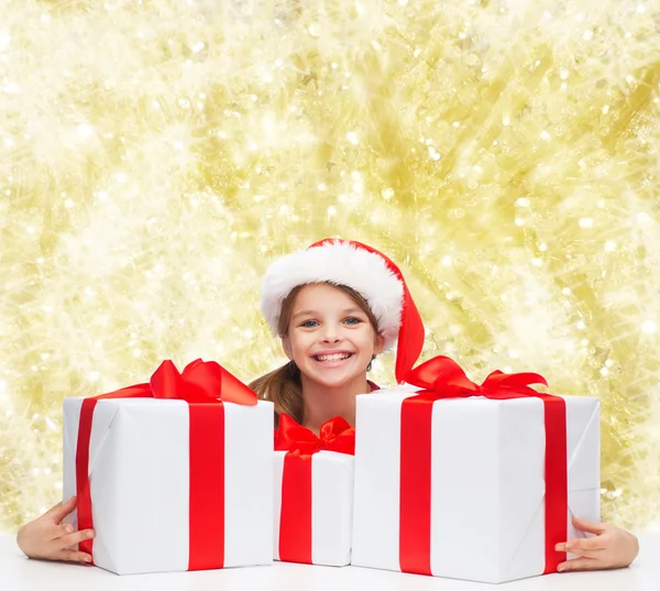 Smiling girl in santa helper hat with gift boxes — Stock Photo, Image