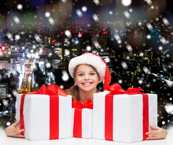 Sonriente chica en santa helper sombrero con cajas de regalo —  Fotos de Stock