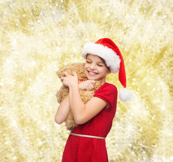 Ragazza sorridente in cappello Babbo Natale con orsacchiotto — Foto Stock