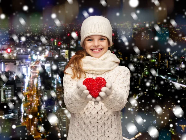 Мечтающая девушка в зимней одежде с красным сердцем — стоковое фото
