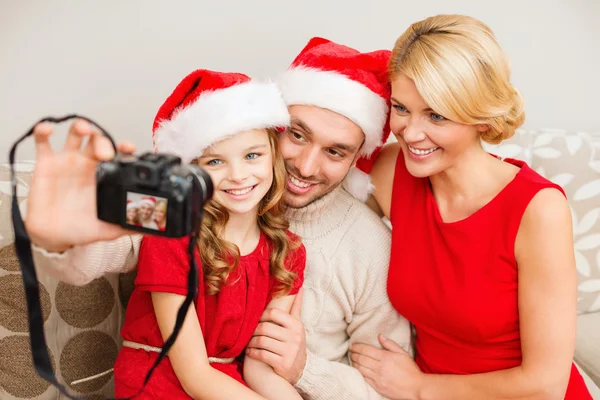 Famille souriante dans santa chapeaux d'aide prendre des photos — Photo