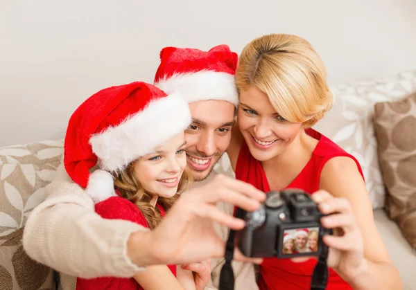 Lächelnde Familie mit Weihnachtsmann-Helfermützen beim Fotografieren — Stockfoto