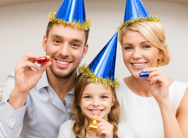 Sonriente familia en sombreros azules soplando cuernos favor —  Fotos de Stock