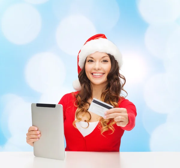 Vrouw in kerstmuts met een tablet-pc en credit card — Stockfoto